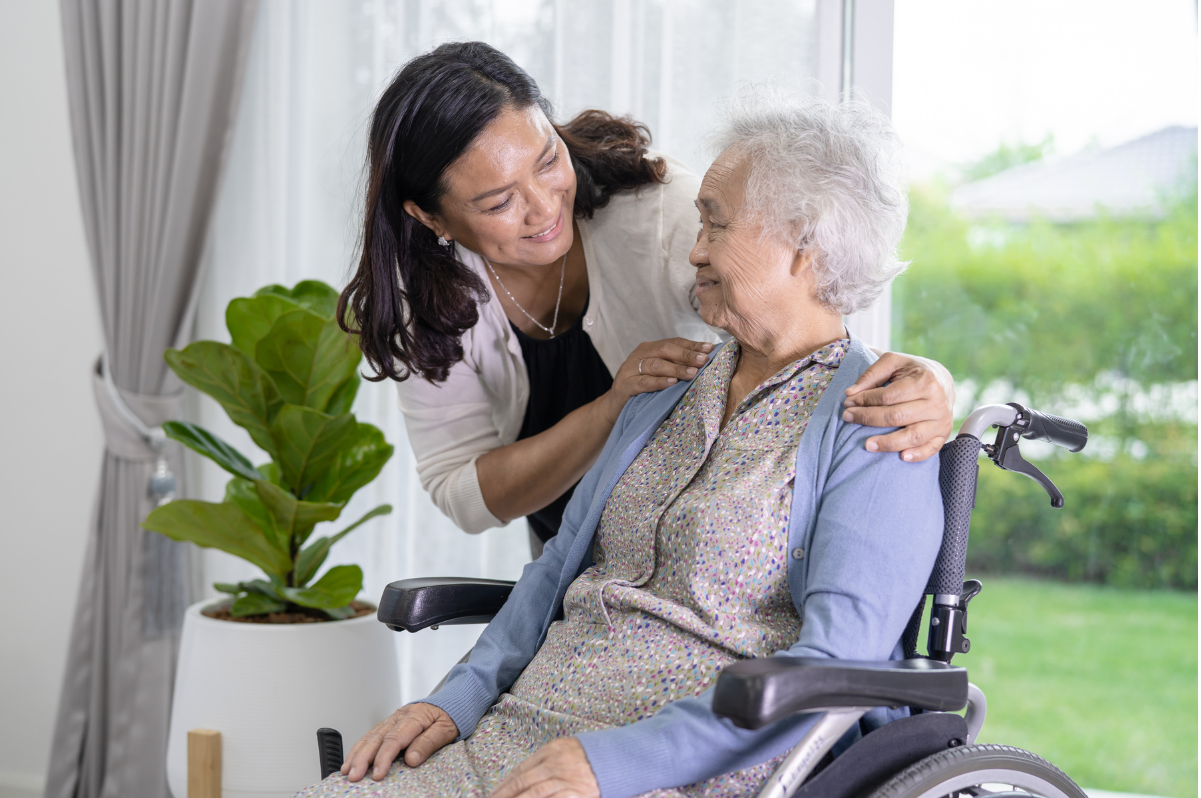 woman in wheelchair looking at woman who has hands on her shoulders